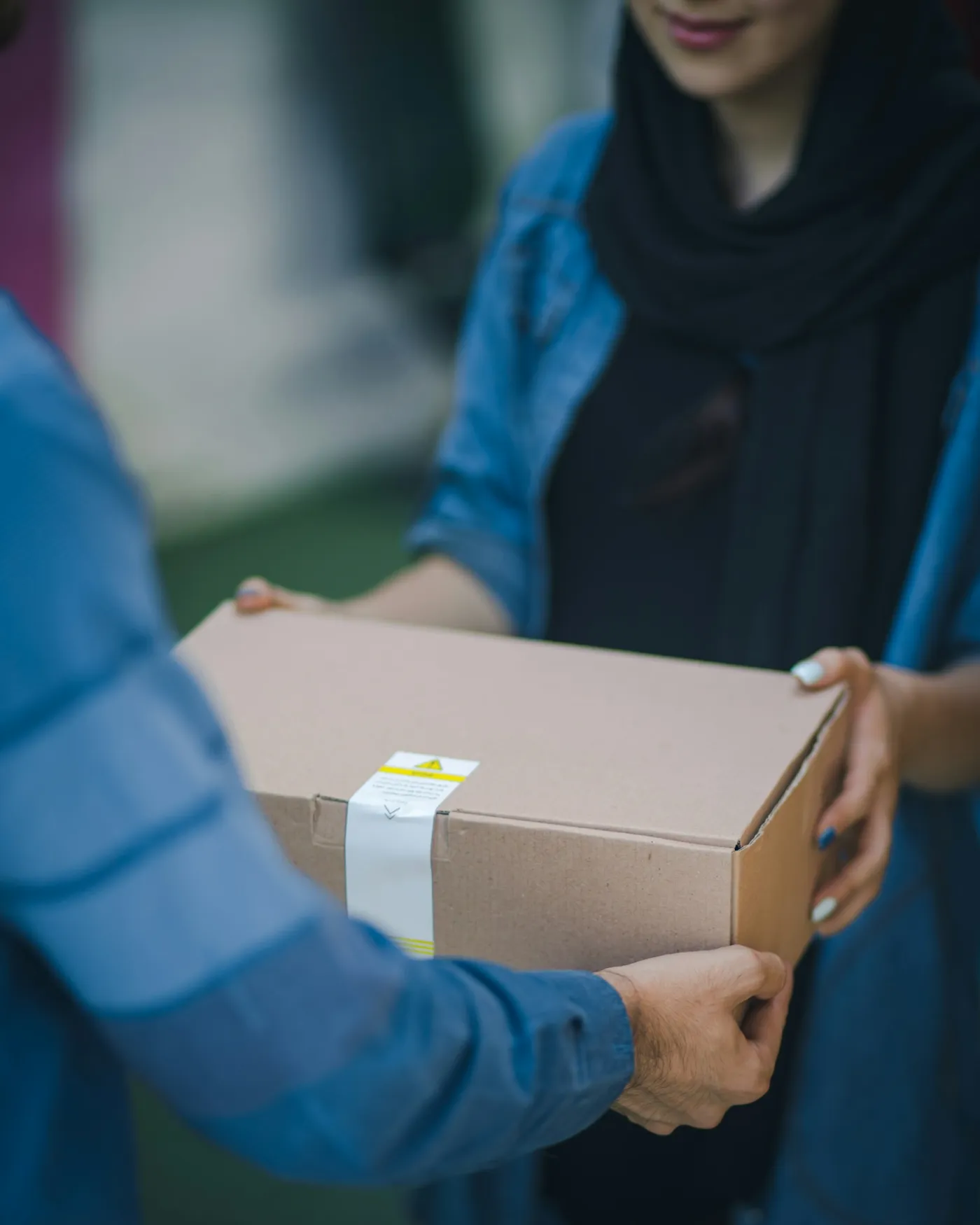 Ein Paket wird persönlich an eine Kundin übergeben